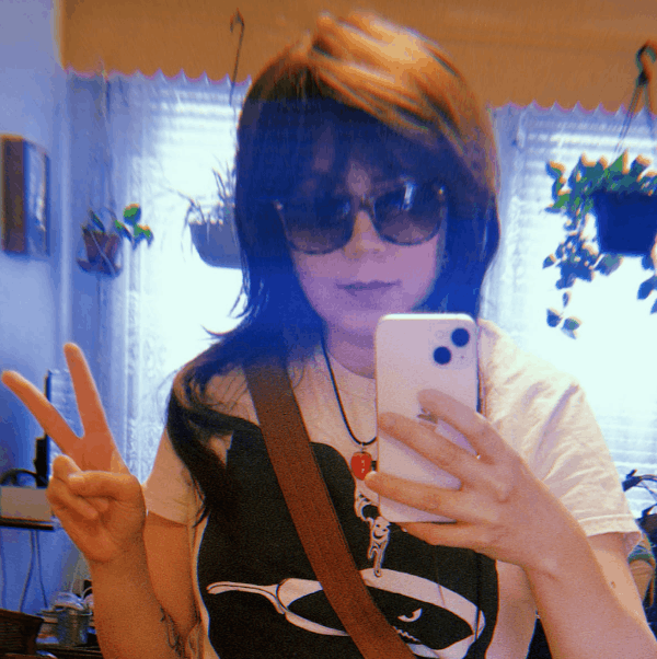 a woman giving a peace sign in the mirror, holding her phone.